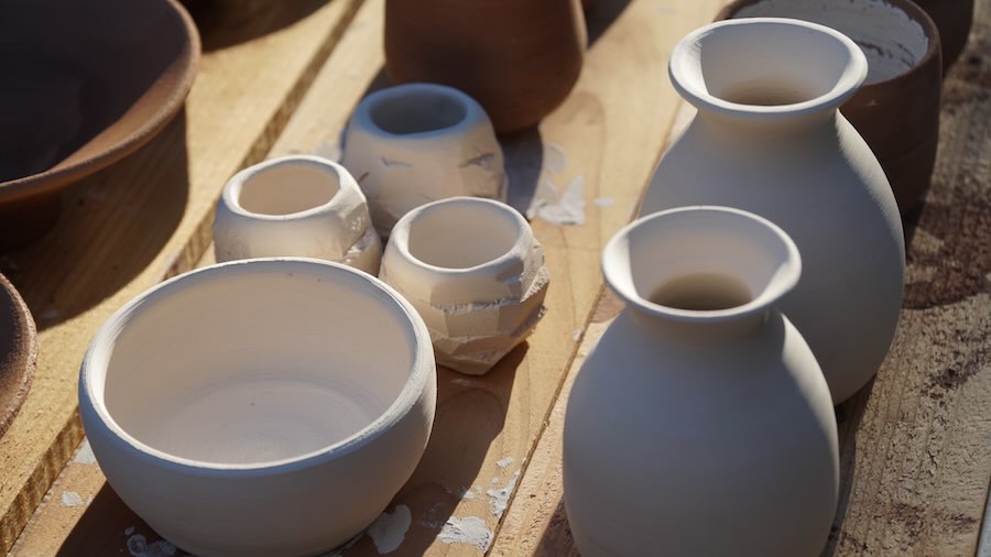 Beginner pottery student shaping clay on wheel
