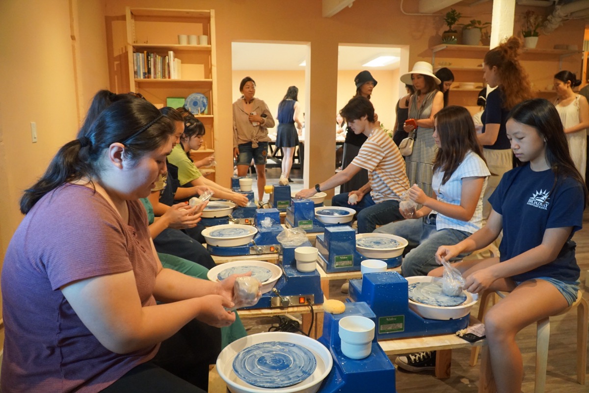 Large group of people at pottery wheels during a team event at Olomana Studios