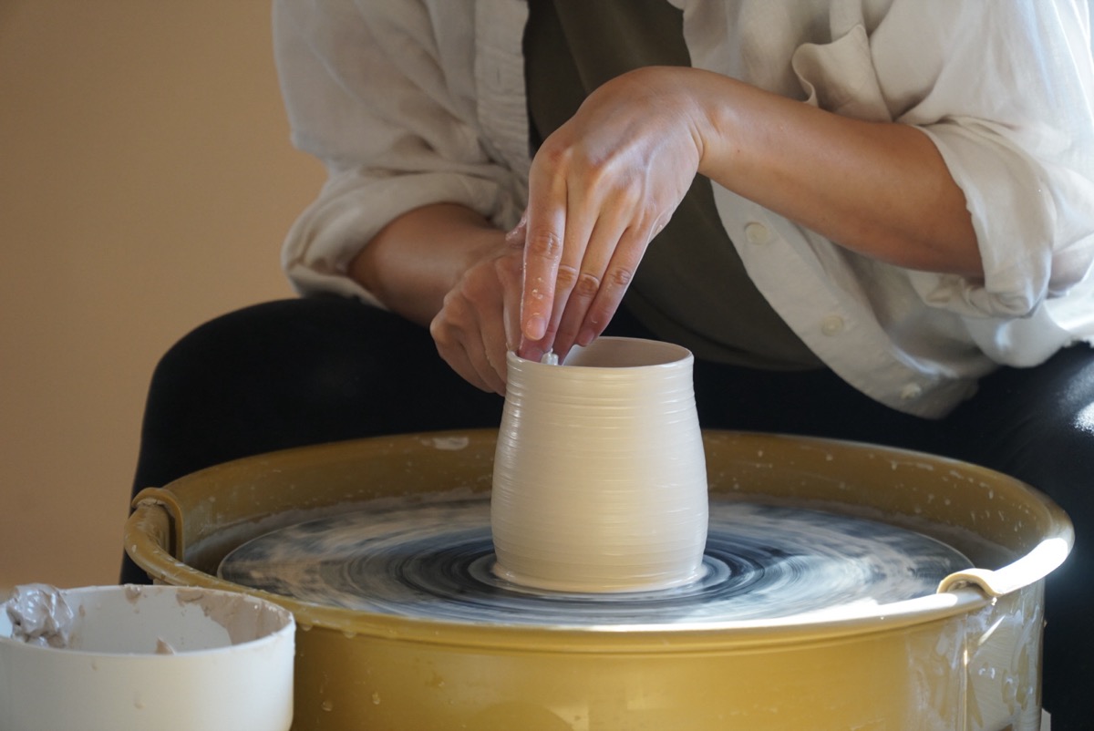 Hands shaping clay on a pottery wheel