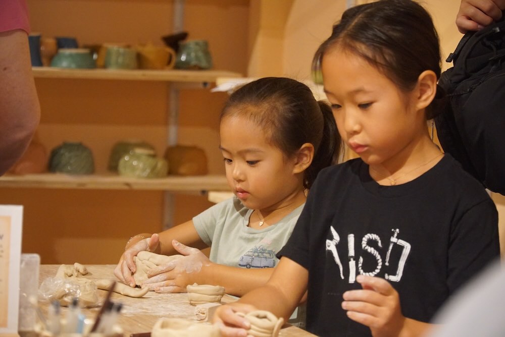 Kids working with clay at the pottery table during summer camp at Olomana Studios
