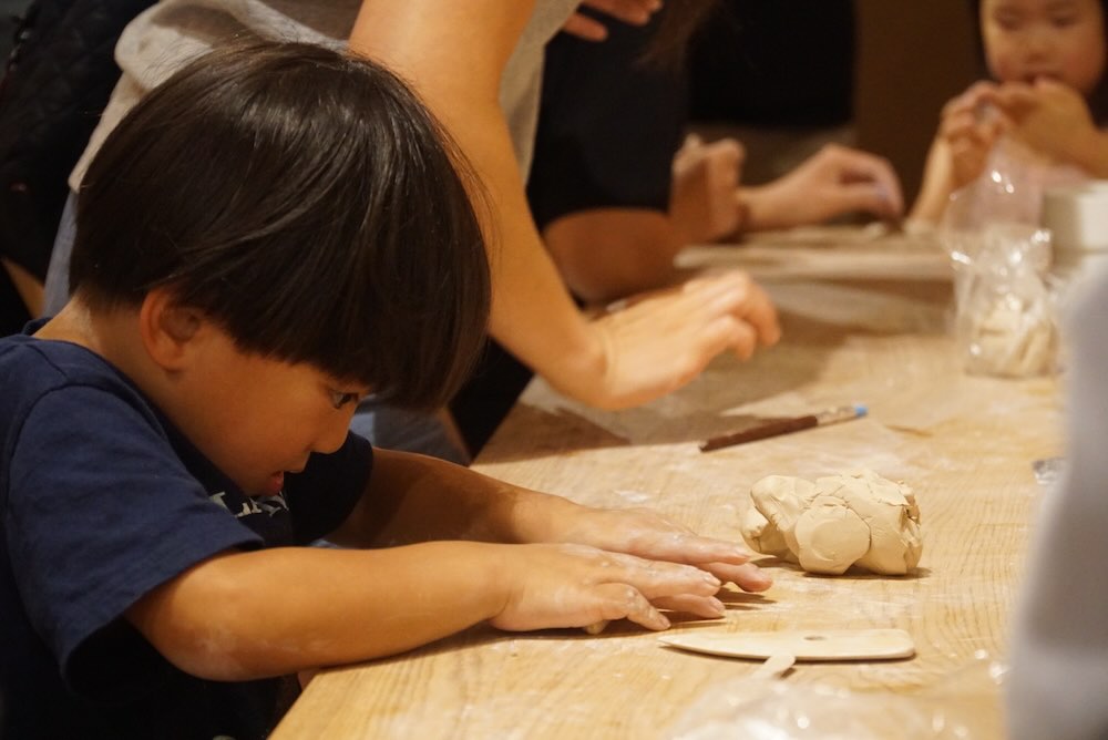 Kids working with clay at the pottery table during summer camp at Olomana Studios in Irvine