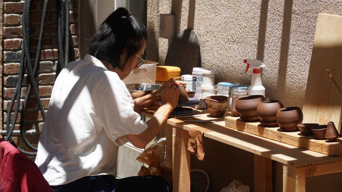 Instructor working at bench with handmade teapots