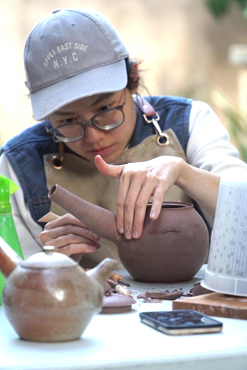 Student shaping a teapot body