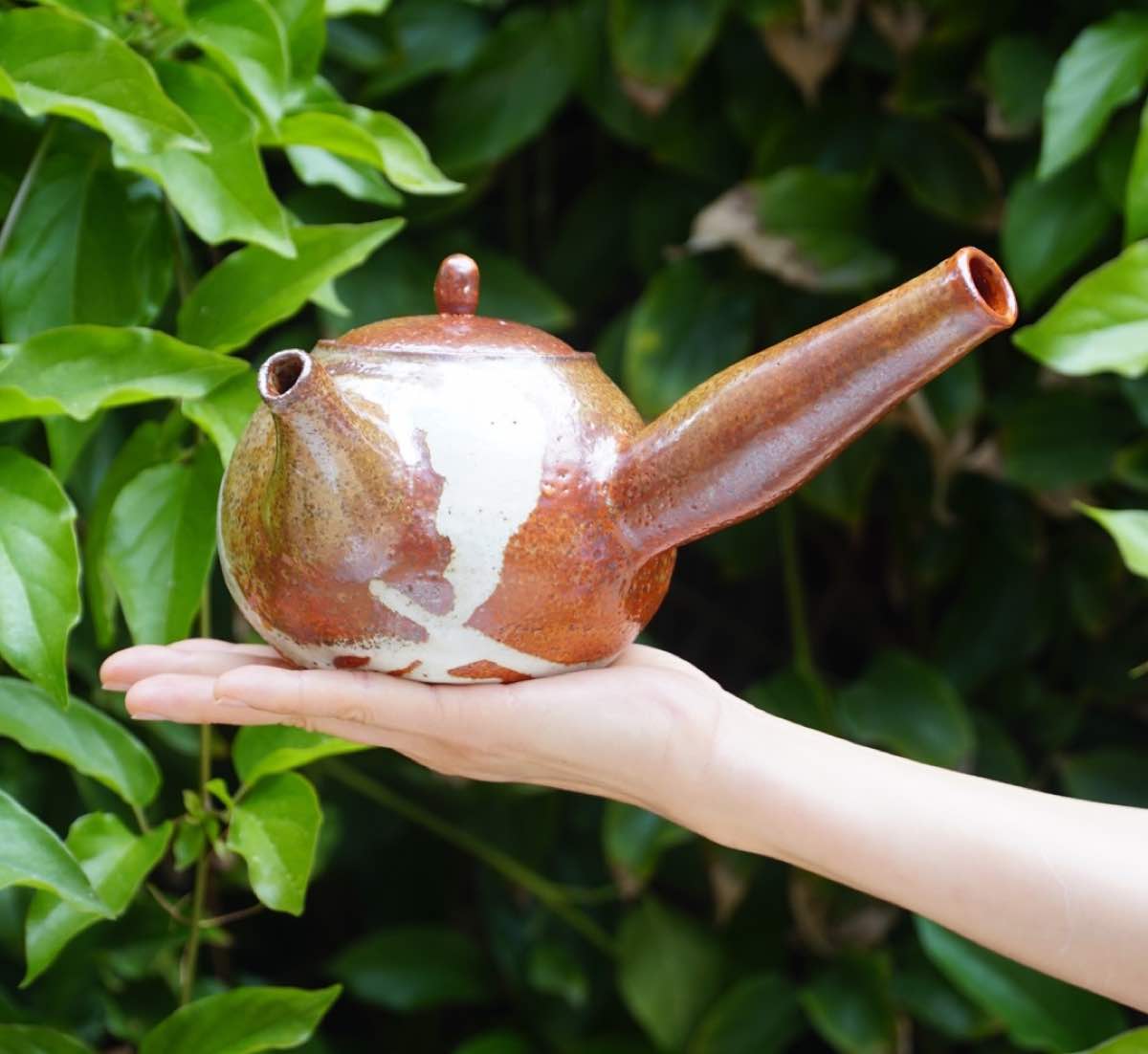 Finished glazed teapot held in hand